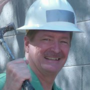 Smiling man wearing a hard hat and holding a hammer